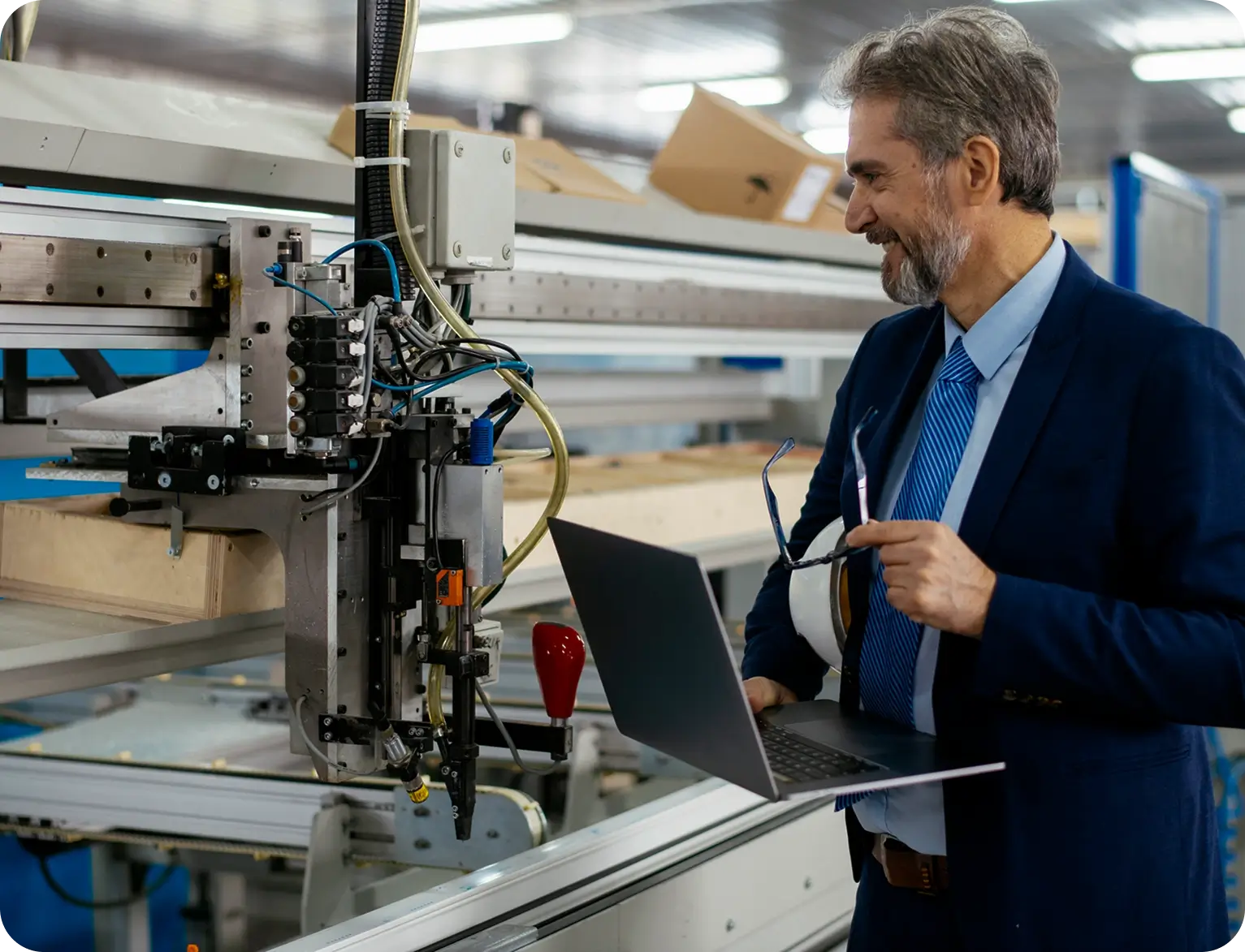 Man with laptop inspecting industrial machinery.