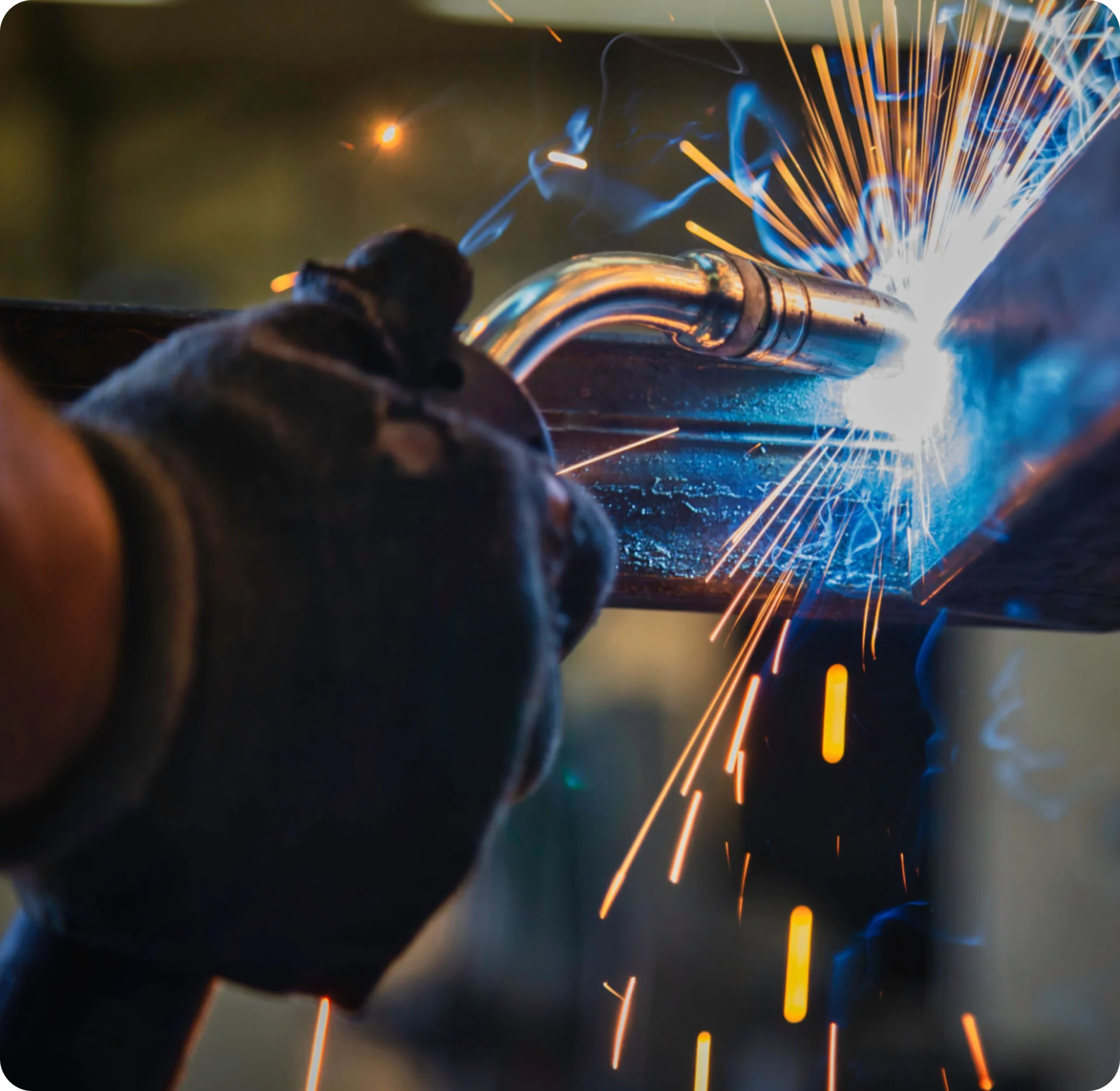 Person welding metal, sparks flying brightly.