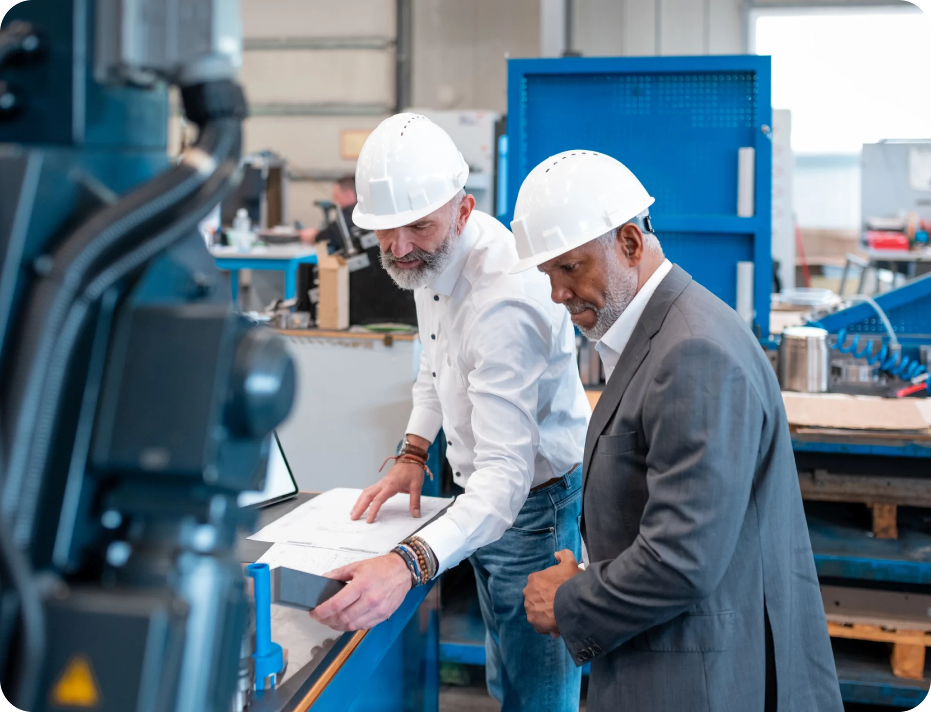 Two engineers reviewing blueprints in factory.